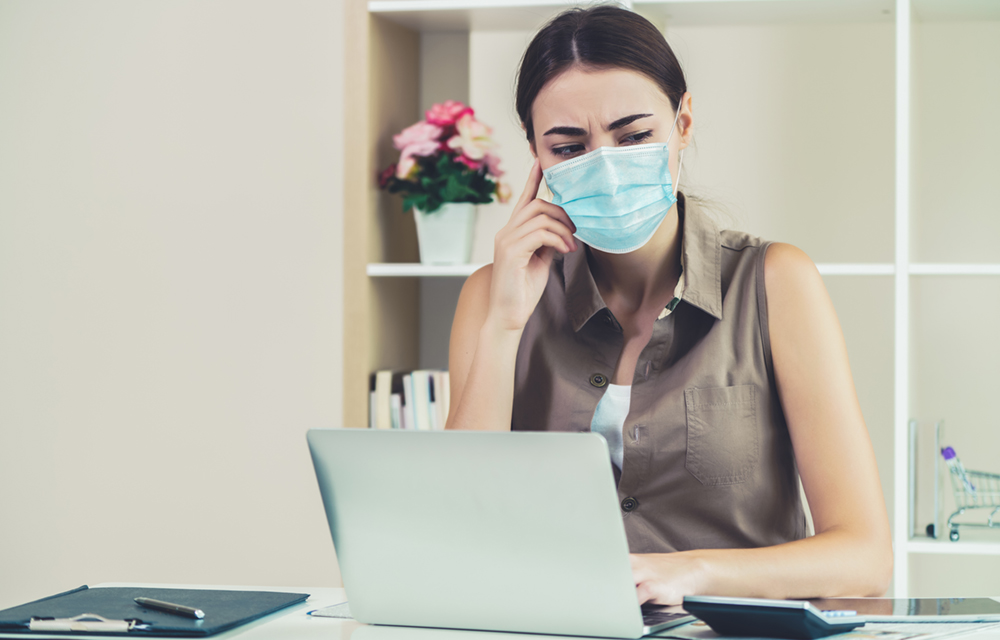 Woman sat at desk with face mask
